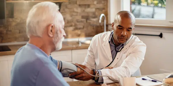 Médico medindo pressão arterial de paciente idoso