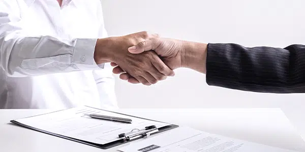 Profissional da saúde dando a mão para novo colaborador da equipe médica.