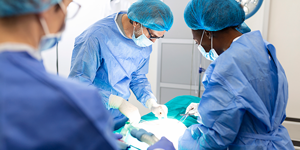 Médicos realizando procedimento em mesa cirúrgica