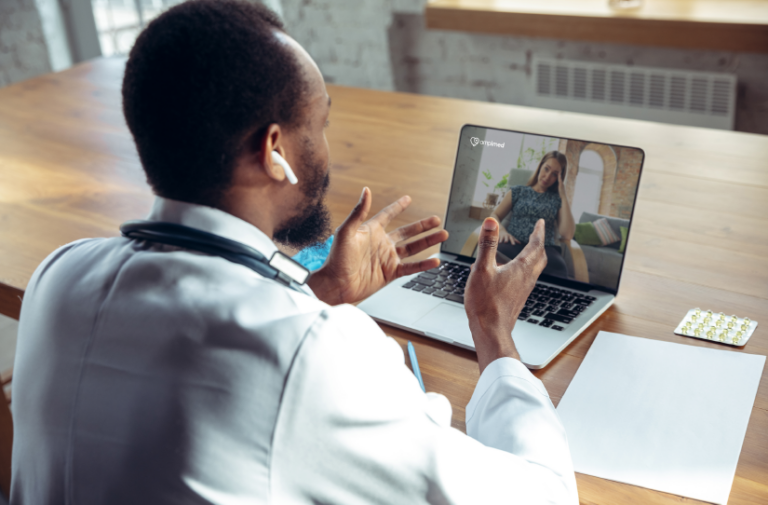 Medico com jaleco e fone conversa por videochamada com paciente no notebook, ilustrando saude digital pos-pandemia