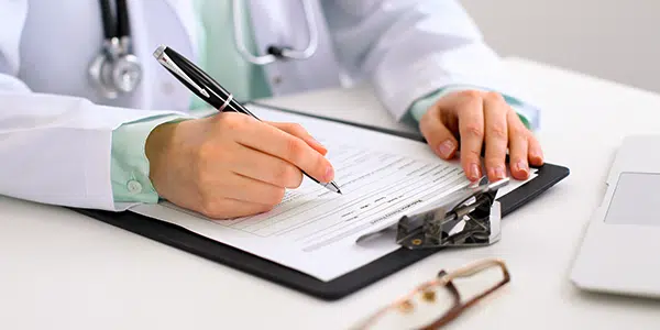 Médico preenchendo ficha de anamnese física em prancheta