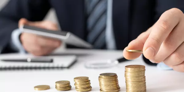 Mão de profissional da saúde contabilizando dinheiro, remetendo às economias em atuar em um coworking médico.