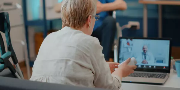 Paciente idosa consultando via telemedicina com médico que atua em coworking médico.