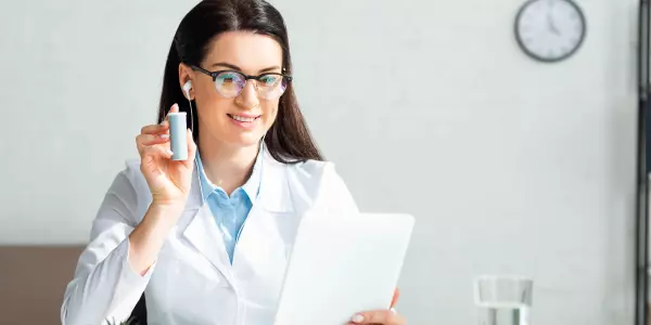 Médica mostrando comprimidos em consulta de telemedicina