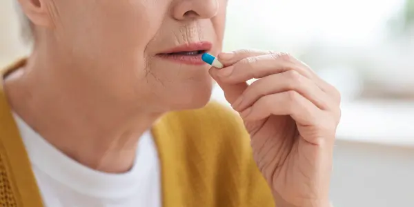 senhora levando medicamento à boca