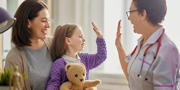 médica acena para criança no colo da mãe