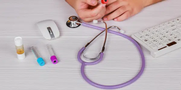 mesa de médico com estetoscópio, mouse e tubos de ensaio de exames