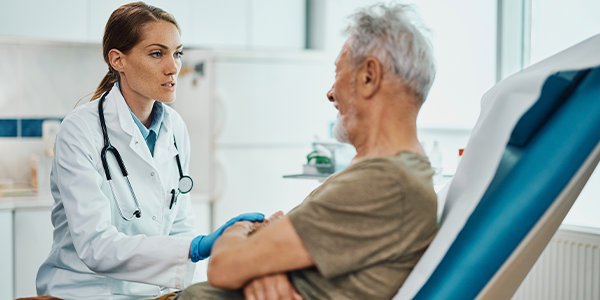 Médica conversando com paciente idoso em maca