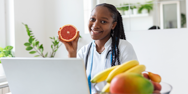 Nutricionista com um computador e frutas na sua frente