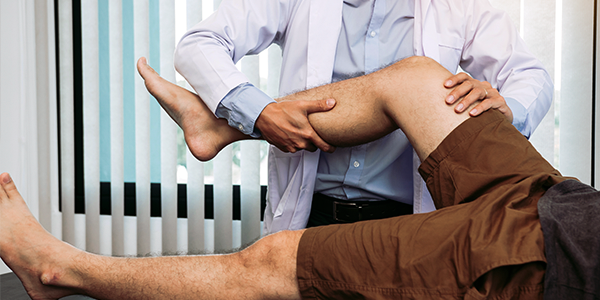 Fisioterapeuta realiza exame físico em perna de paciente