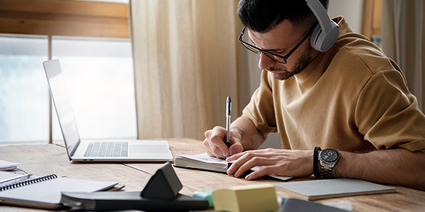 Homem estudando estratégias de gestão de tempo enquanto faz anotações em papel