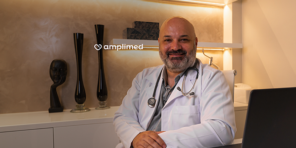 Dr. Asdrubal em seu consultório com estetoscópio no pescoço e sorrindo para a câmera