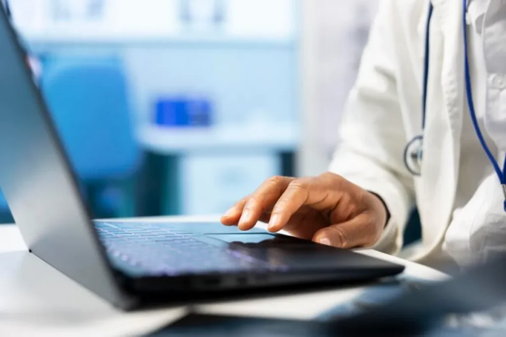 Médico usando software médico em notebook no consultório